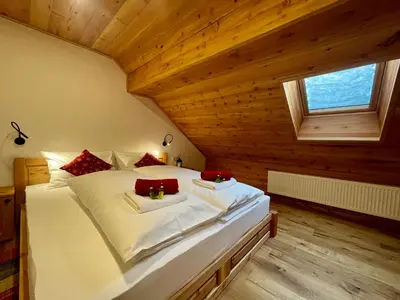 a bedroom with a large white bed with red pillows at Hotel ŠURC in Kranjska Gora