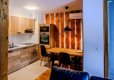 a kitchen with wooden cabinets and a wooden table at APARTMA JEREBIKA ŠT. 20 in Pohorje