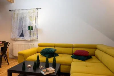 a yellow couch in a living room with a table at Apartments Gozdni Raj Rogla in Oplotnica