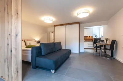 a bedroom with a bed and a couch and a chair at Apartments Ursus in Bled