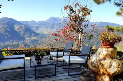 a deck with chairs and tables and a view of mountains at House Pucnk-beautiful countryside in Železniki