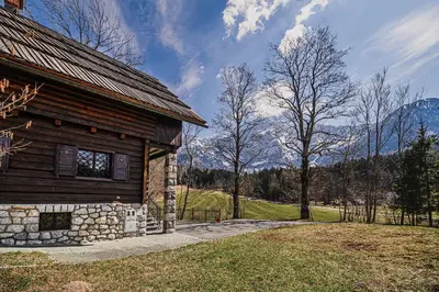 a log cabin with mountains in the background at Holiday Home Iris in Zgornje Jezersko