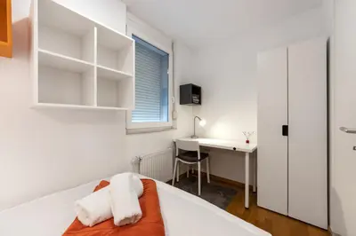 a bedroom with a bed and a desk and a window at Attractive Njegoševa Apartment with a Balcony in Ljubljana