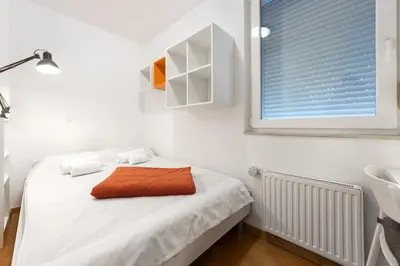 a white bedroom with a bed with a window at Attractive Njegoševa Apartment with a Balcony in Ljubljana