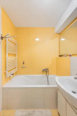 a yellow bathroom with a tub and a sink at Attractive Njegoševa Apartment with a Balcony in Ljubljana