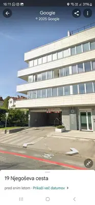 a white building with a parking lot in front of it at Attractive Njegoševa Apartment with a Balcony in Ljubljana
