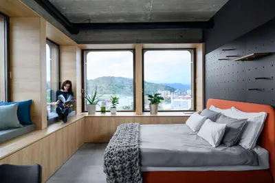 a woman sitting in a window seat in a bedroom at Delo 2.0. in Ljubljana