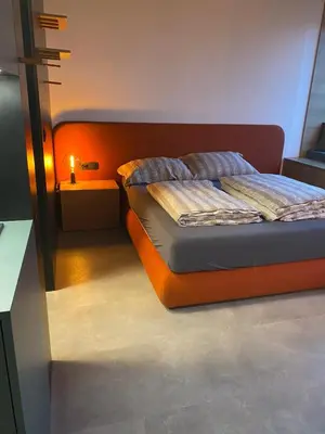 a bed with an orange headboard in a room at Delo 2.0. in Ljubljana