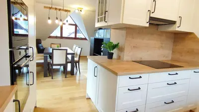 a kitchen with white cabinets and a dining room at Apartmaji Dora in Mojstrana