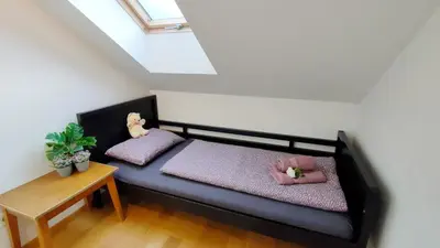a small bedroom with a black bed with pink pillows at Apartmaji Dora in Mojstrana