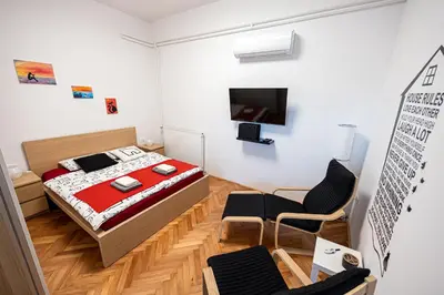 a bedroom with a bed and two chairs and a tv at That Cat Flat - free parking, near city center, cats! in Ljubljana