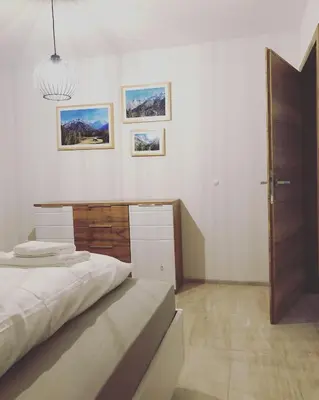 a white bedroom with a bed and a desk at ALPS Apartments in Kranjska Gora