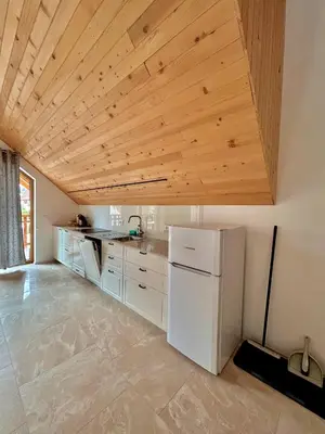 a kitchen with a white refrigerator and a wooden ceiling at ALPS Apartments in Kranjska Gora