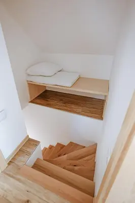a room with wooden floors and a bed on a shelf at Apartments Čenda in Železniki