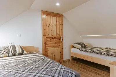 a bedroom with two beds and a wooden door at Apartments Čenda in Železniki