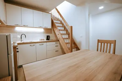 a kitchen with a wooden table and a staircase at Apartments Čenda in Železniki