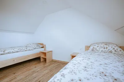 a bedroom with two beds and a white wall at Apartments Čenda in Železniki