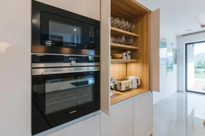 a kitchen with a microwave and a black oven at HIRUNDO- villa with saunas and hot tub in Sela pri Dobovi