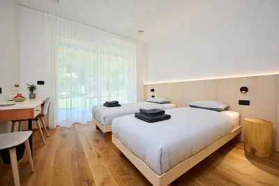 two beds in a room with a desk and a table at Na trati Pension in Črna na Koroškem