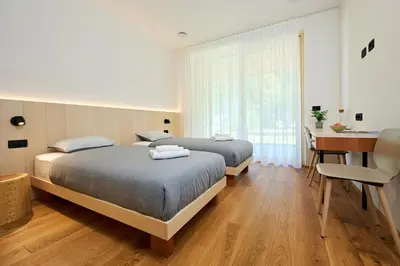 two beds in a bedroom with a desk and a table at Na trati Pension in Črna na Koroškem