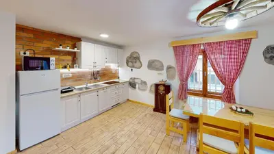 a kitchen with a white refrigerator and a table with chairs at hiša Margit, Rateče 150 in Rateče