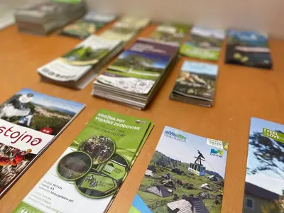 a wooden table with brochures on top of it at Prijeten prostoren apartma v hiši in Pivka