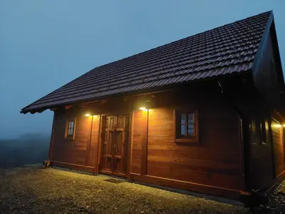 a small wooden cabin with two windows at night at Hiška oddiha - Rest house in Sromlje