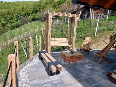 a wooden bench and two chairs on a patio at Hiška oddiha - Rest house in Sromlje