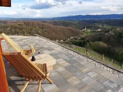a patio with two chairs and a table on a roof at Hiška oddiha - Rest house in Sromlje
