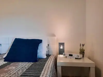 a bedroom with a bed with a blue pillow and a table at Vineyard cottage Kulovec in Uršna Sela