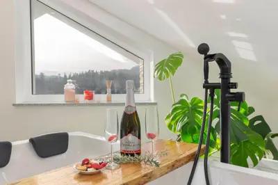 a bottle of wine and two glasses on a table at Holiday House Vikend in Polzela