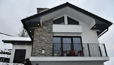 a white house with a balcony with two red chairs at Holiday House Vikend in Polzela
