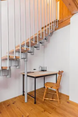 a table under a staircase with a wooden chair at Svisla in Kranj