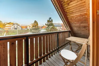 a wooden balcony with a wooden table and a chair at Svisla in Kranj