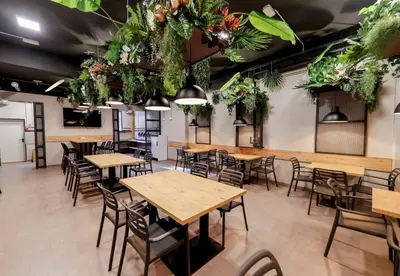 a restaurant with tables and chairs and plants hanging from the ceilings at Hostel Veronika Celje in Celje