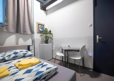 a room with a bed and a table and chairs at Hostel Veronika Celje in Celje