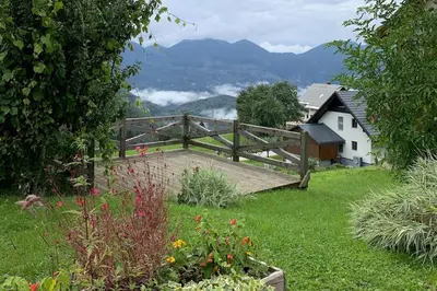 a wooden bridge in a garden with a house and mountains at Dandelion House in Podjelje