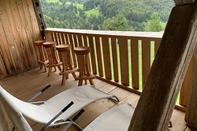 a porch with three chairs and a table on a deck at Dandelion House in Podjelje