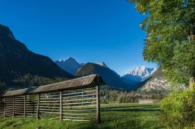 a barn in a field with mountains in the background at Ela Apartments - 1 in Kranjska Gora