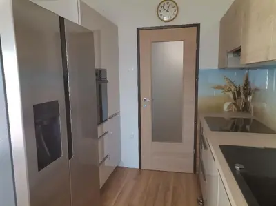a kitchen with a door and a clock on the wall at Ela Apartments - 1 in Kranjska Gora