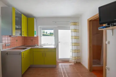 a kitchen with yellow cabinets and a window at Ela Apartments - 2 in Dovje