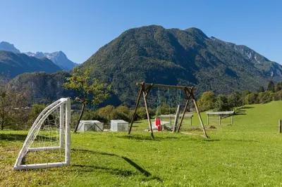 an empty swing set in a field with a mountain at Ela Apartments - 2 in Dovje