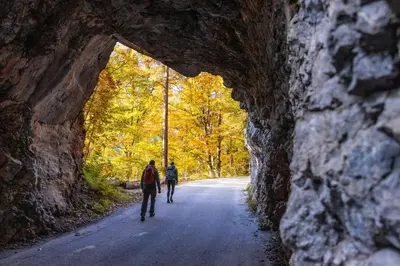 two people walking down a road through a stone tunnel at Sport & Sunny Cosy Alpine Retreat in Kranjska Gora