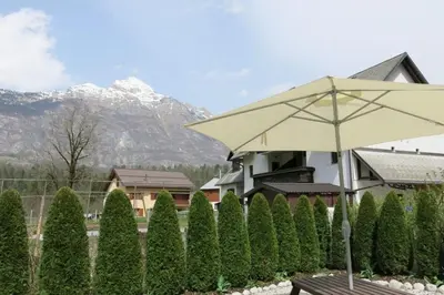 a table with an umbrella in front of a hedge at Lepa Soca House in Čezsoča