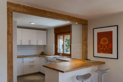 a kitchen with white cabinets and a wooden counter top at Mostnica Cottage in Bohinj
