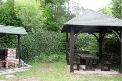 a picnic table and a gazebo in a park at Mostnica Cottage in Bohinj
