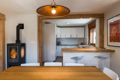 a kitchen with a wooden table and a wood stove at Mostnica Cottage in Bohinj