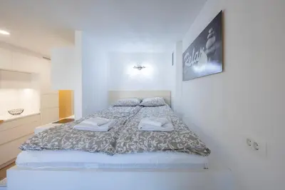 a bedroom with a large bed in a white room at Relax Studio Kranjska Gora in Kranjska Gora