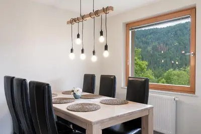 a dining room table with black chairs and a window at Sava View 8 in Ribno