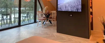 a living room with a table and a tv on the wall at Pine Tree Holiday House in Gozd Martuljek
